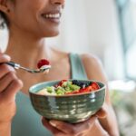 Close,Up,Of,Athletic,Woman,Eating,A,Healthy,Fruit,Bowl