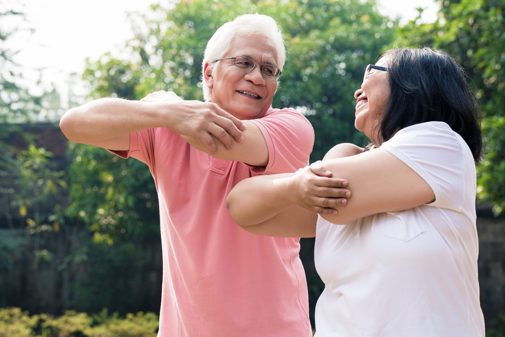 Senior,Man,Assisting,His,Wife,During,Warming,Up,Exercises,For