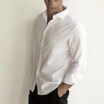 Michael Klim smiling in a white shirt against a plain light background for a Greencare and Klim Foundation awareness post.