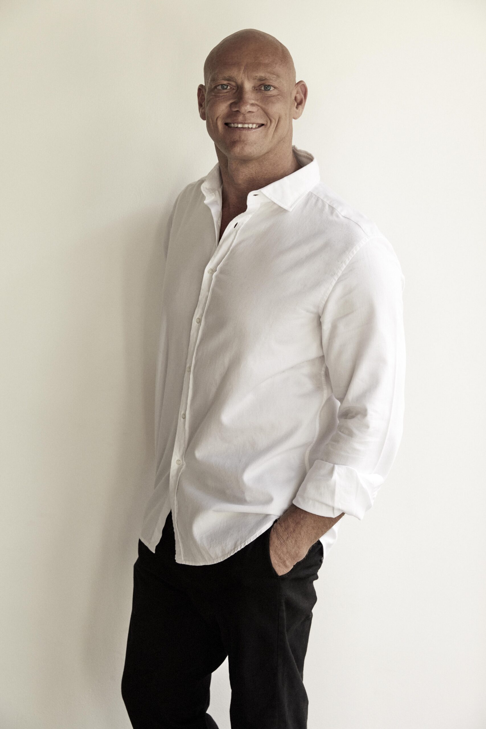 Michael Klim smiling in a white shirt against a plain light background for a Greencare and Klim Foundation awareness post.