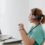 Healthcare practitioner wearing a headset during a telehealth consultation on laptop.